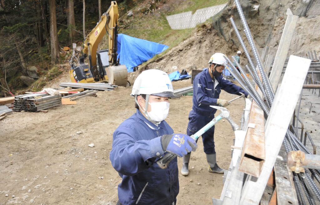 写真／治山工事現場で、新堤の枠組みを作る伊藤妃与乃さん（手前）。外国籍の作業員も含め、多様な職場環境づくりが進む＝中津川市川上