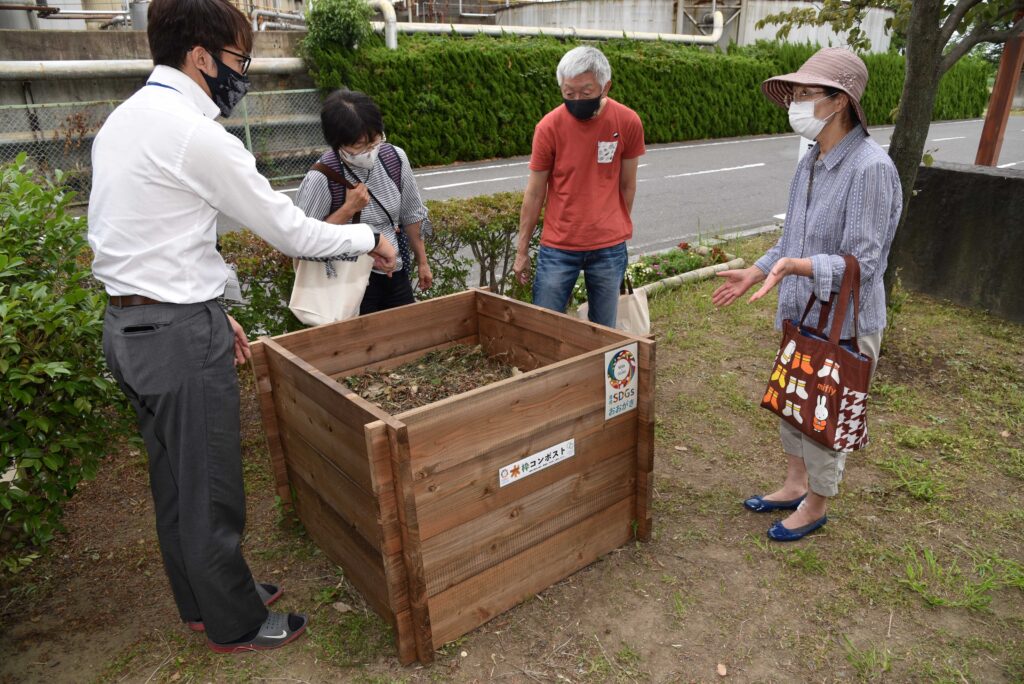 大垣市が推進する木枠コンポストを前に、市職員から説明を聞く市民＝大垣市米野町、市クリーンセンター